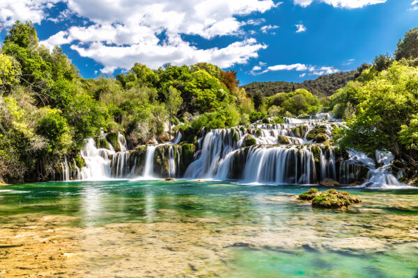 Parcul Național Krka înconjurat de copaci și un cer albastru Parcul Național Krka înconjurat de copaci și un cer albastru