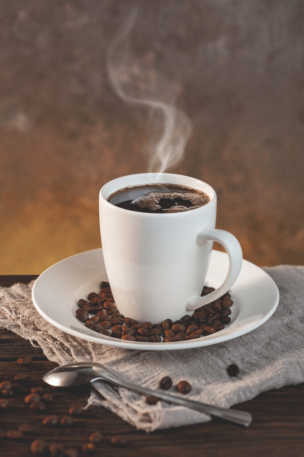 O ceașcă de cafea pe o farfurie cu boabe și o lingură O ceașcă de cafea pe o farfurie cu boabe și o lingură