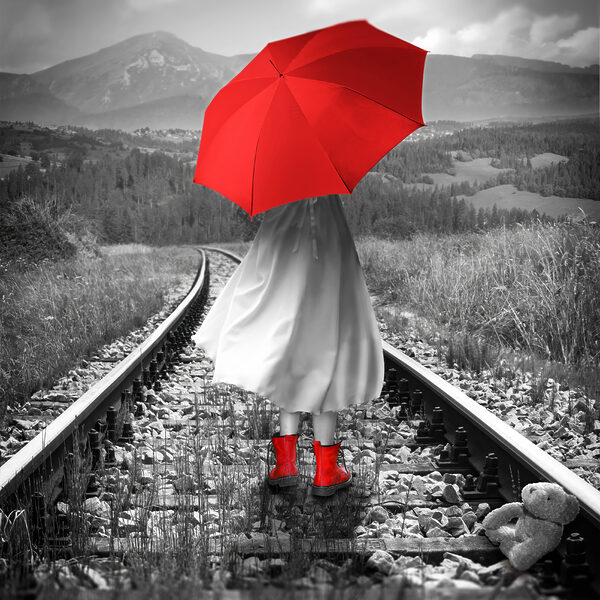 O persoană cu o umbrelă roșie pe o linie de tren O persoană cu o umbrelă roșie pe o linie de tren