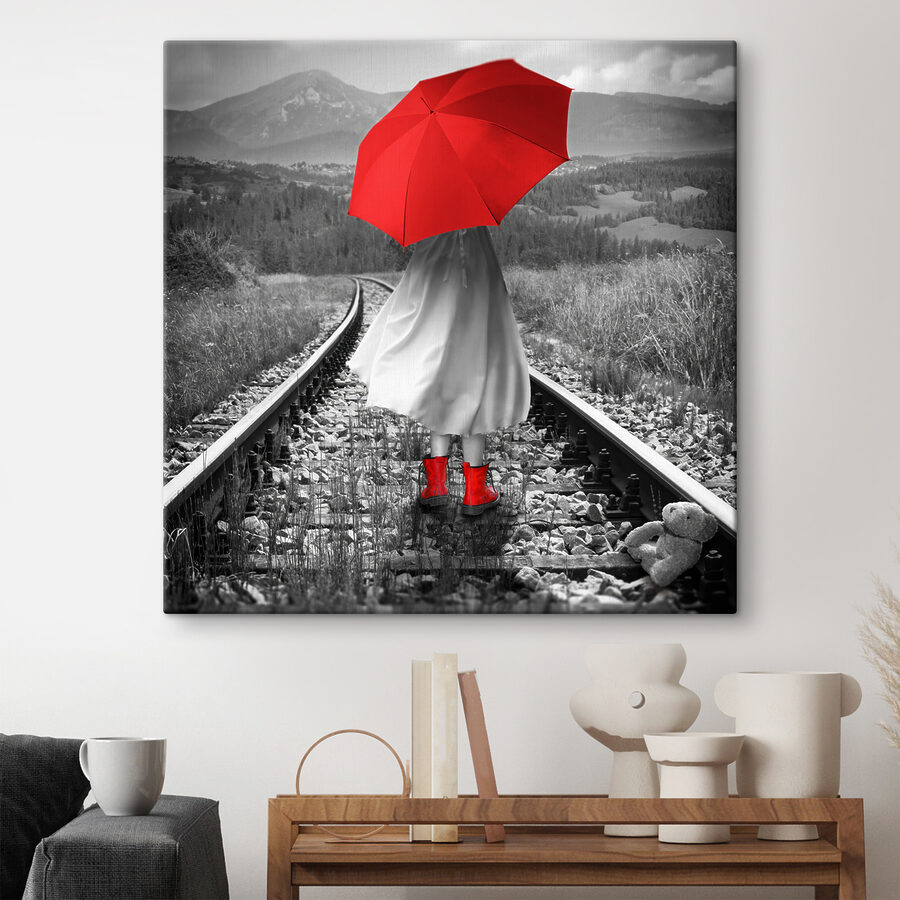 O persoană cu o umbrelă roșie pe o linie de tren
