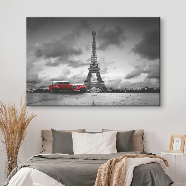 A red car parked in front of a large tower